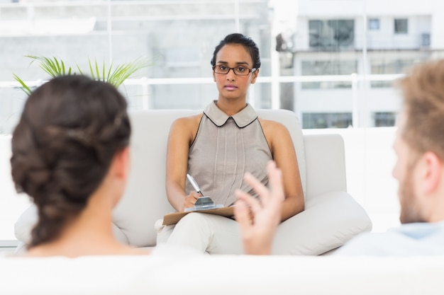 Therapist listening to unhappy couple and taking notes