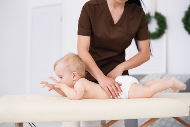 Il terapista fa massaggio a un bambino piccolo nella moderna e accogliente camera. concetto di assistenza sanitaria e medica.