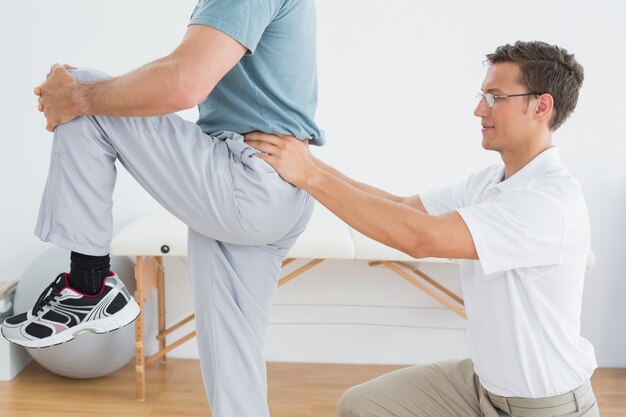 Therapist massaging mans lower back in gym hospital