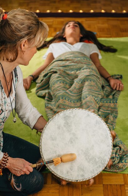 Photo therapist playing drum by young woman at spa