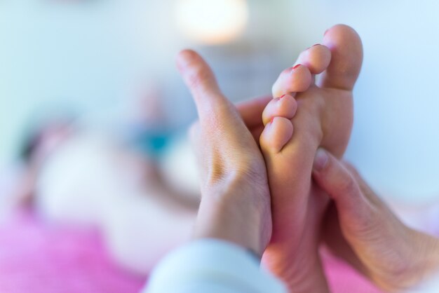 Photo therapist's hands massaging female foot