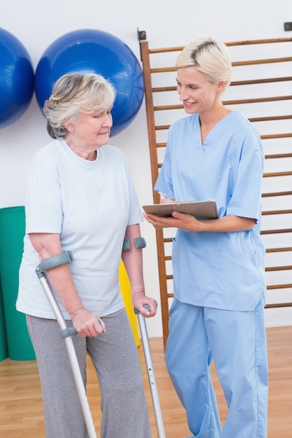 Foto terapista e donna senior che esaminano lavagna per appunti