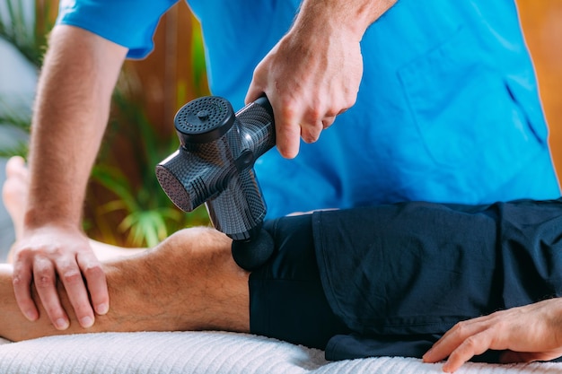 Therapist Treating Patient's Quadriceps Muscle with Massage Gun