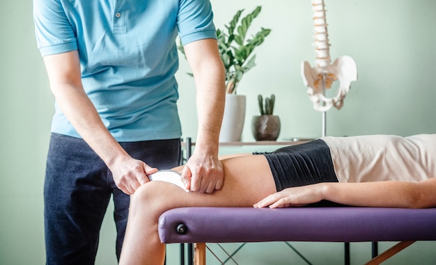 Therapist using IASTM instrument for soft tissue treatment on the leg of a female patient