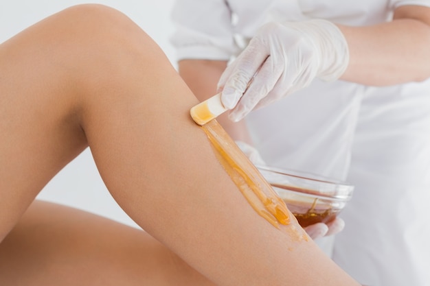 Therapist waxing womans leg at spa center