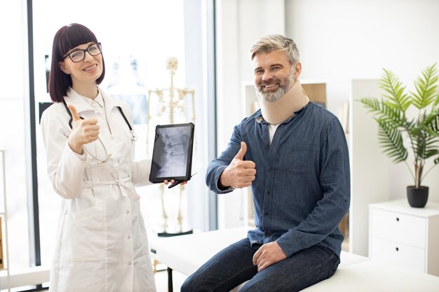 Foto terapista con tablet in posa nell'ufficio del medico con il paziente