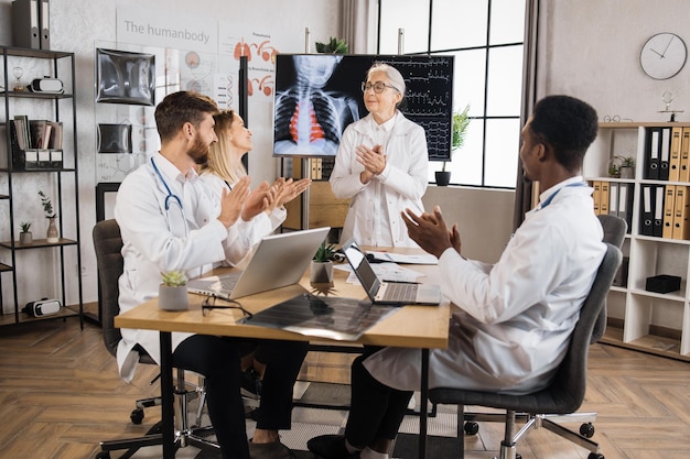 Photo therapists clapping after successful speech of senior woman