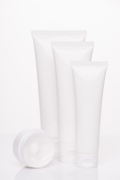 Therapy bodycare freshness nature concept. Vertical photo of collection of different size tubes with cream isolated over pure white background