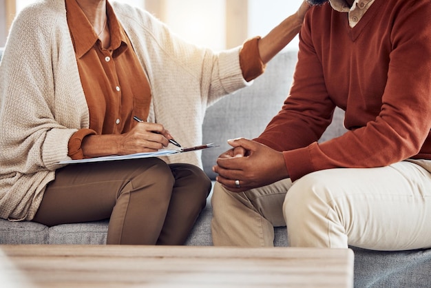 Therapy counseling and grief with a black man patient and woman counselor talking in session Writing hands and female mental health therapist helping a male client with depression or anxiety