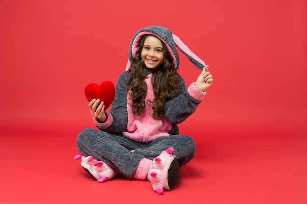 Therapy and love. Happy child in bunny pajamas hold red heart. Cardio diagnostics. Cardio surgery. Cardiovascular disease. Cardiac activity. Pediatric cardiology. Health care. Healthcare.