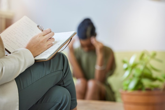 Foto psicologa della scrittura terapeutica e donna di colore triste con mal di testa da stress e burnout in ufficio consultazione del terapista di supporto e controllo della salute mentale con il lavoro psicologico di un paziente su un divano