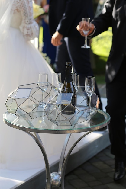 There are glasses and a bottle of champagne on the glass table.