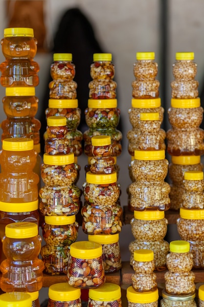 There are many jars of organic, natural honey on the counter for sale. Different honey, different colors in plastic cans are ready for sale at the honey fair. Nuts filled with honey.