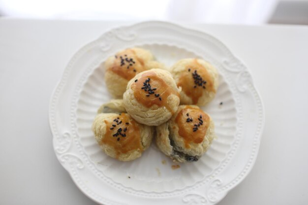 Foto ci sono dei deliziosi dolci di tuorlo di uovo di sesamo nero appena cotti sul piatto sul tavolo.