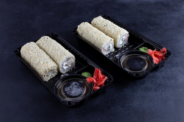 There are sushi in a package on the table. On a black background.
