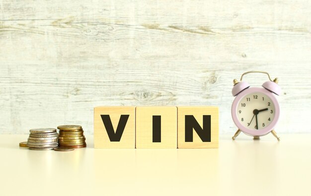 На столе рядом с монетами лежат три деревянных кубика с буквами. Слово VIN. На сером фоне.