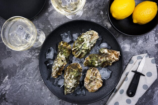 There are two glasses of white wine and freshly caught oysters on the table