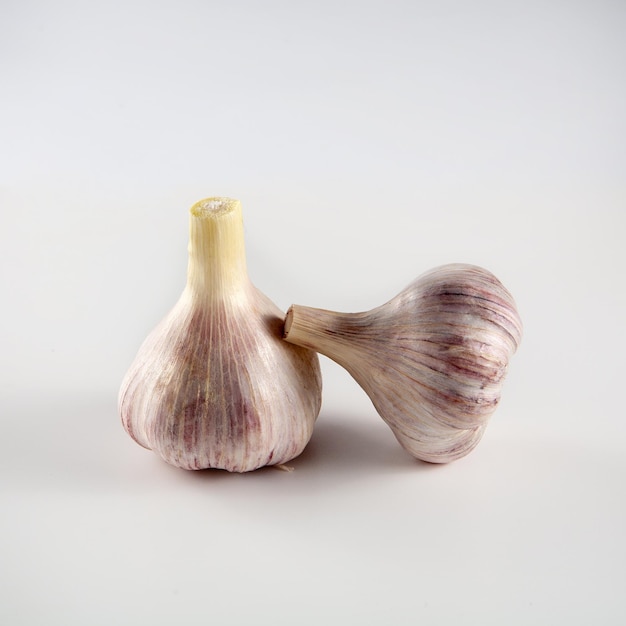 There are two heads of garlic on the table. On a white background.