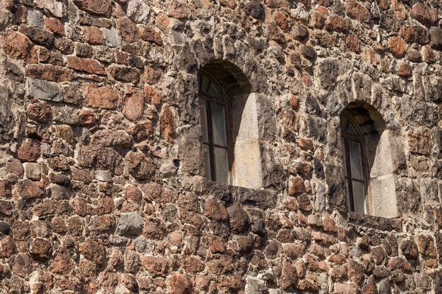 There are two Windows in the old stone wall