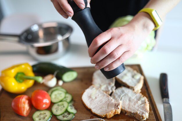 There are vegetables and bacon on cutting board to which spices are added. Cooking healthy food at home concept