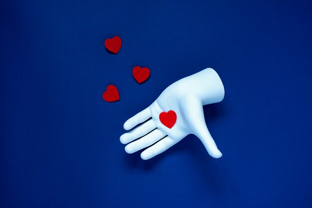 В белой руке красное сердце. на синем классическом фоне. концепция дня святого валентина