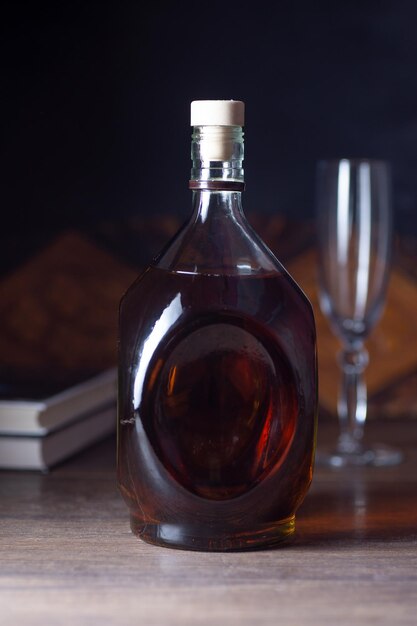 There is a bottle of wine on the table. Behind the glass and books.