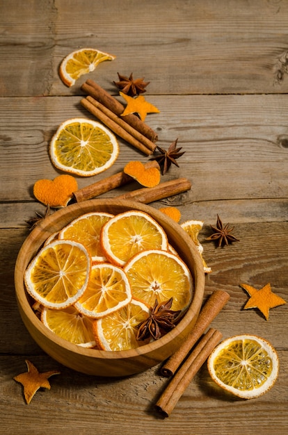 There is a bowl with orange rings on a wooden table. Christmas decoration.