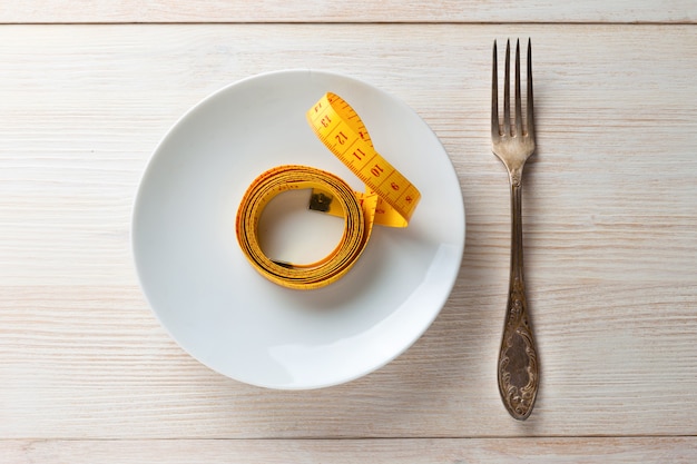 There is a fork and measuring tape on the saucer. The concept of a healthy lifestyle