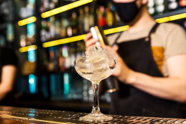 Foto c'è un bicchiere con ghiaccio sul bar il bicchiere viene raffreddato prima di servire il cocktail foto orizzontale