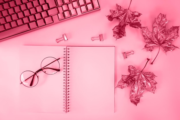 There is a notebook a keyboard maple leaves on the table the color of the year