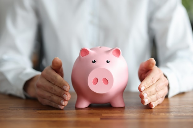 There is pink piggy bank inside human hands