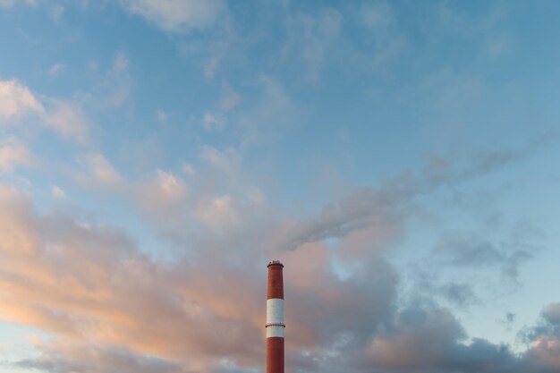 There is smoke coming from a chimney from a thermal power plant a beautiful sky during sunrise