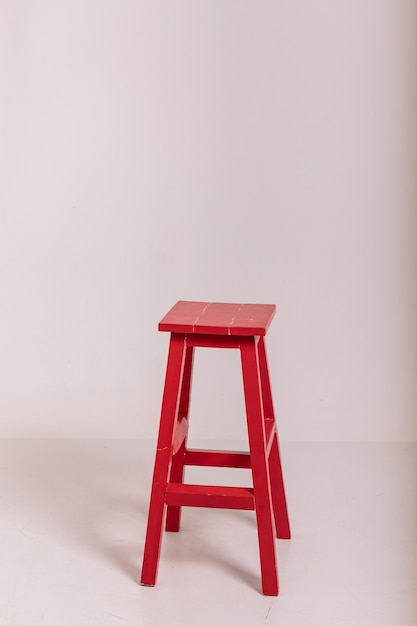 There is a tall red chair in a bright room