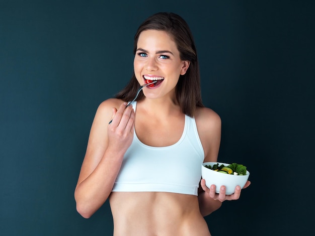 Theres always room for healthy food Studio portrait of an attractive young woman eating a salad against a dark background