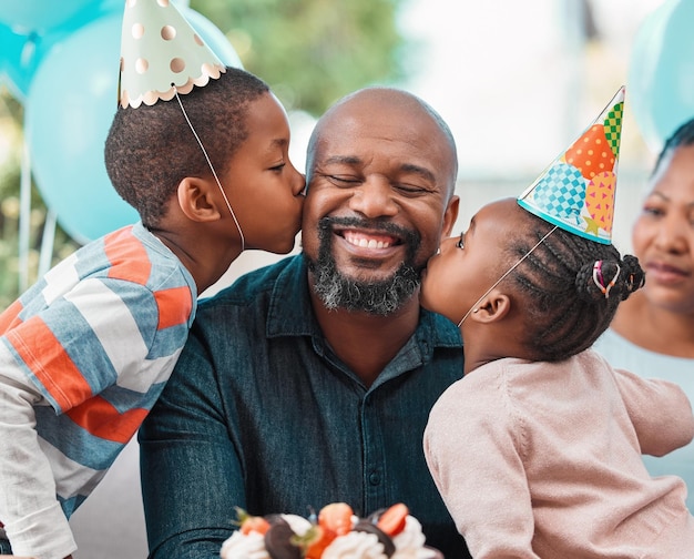 가족보다 더 좋은 선물은 없습니다. 생일 파티에서 성숙한 남자의 뺨에 키스하는 두 아이의 샷