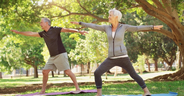 Non c'è un piano di pensionamento per allenarsi foto a figura intera di una coppia senior felice che fa yoga insieme al parco