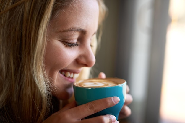 Non c'è niente di meglio dell'odore del caffè appena preparato primo piano di una giovane donna attraente che si gode un cappuccino in una caffetteria