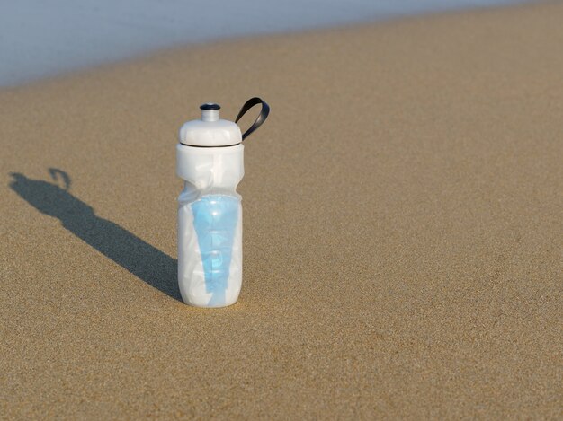 Thermal sport bottle on the sand beach. Copy space.