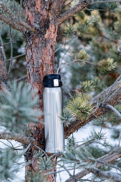 Foto thermische fles op een kerstboom tak thermos voor dranken verticaal frame