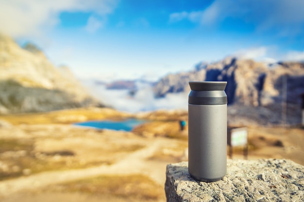 Foto termo tazza in piedi sulla roccia con vista sulle dolomiti, italia. concetto di viaggio e avventura.