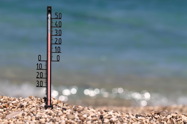 Photo thermometer on a beach shows high temperatures