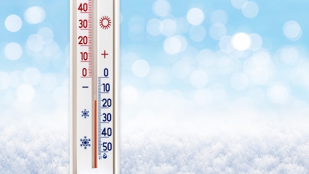 Термометр на размытом зимнем фоне показывает 15 градусов ниже нуля