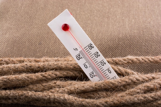 Thermometer on a brown rope on a fabric background