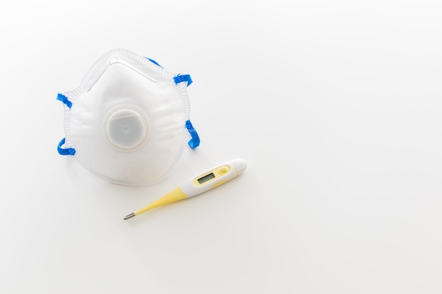 Thermometer and mask for coronavirus protection with copyspace on white background