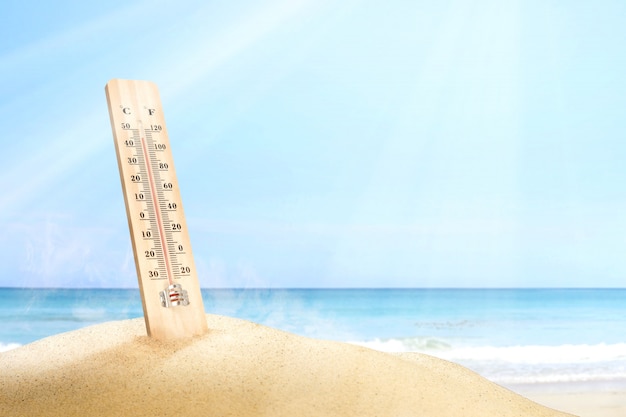 Thermometer measuring the temperature on the beach with a blue sky background