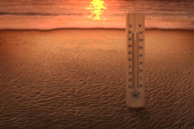 일몰 하늘 배경으로 해변의 온도를 측정하는 온도계