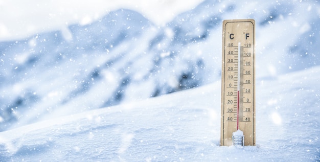 Thermometer on the mountains in the snow shows temperatures below zero. Low temperatures in degrees Celsius and fahrenheit in snowy weather.