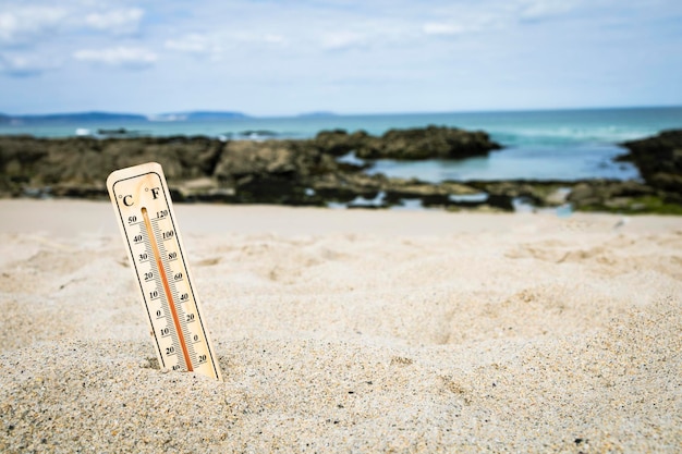 Thermometer op het strand die hoge temperaturen markeert. Klimaatverandering. Opwarming van de aarde. Ecologisch probleem