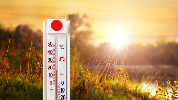 The thermometer shows 20 degrees of heat in nature near the river during sunset