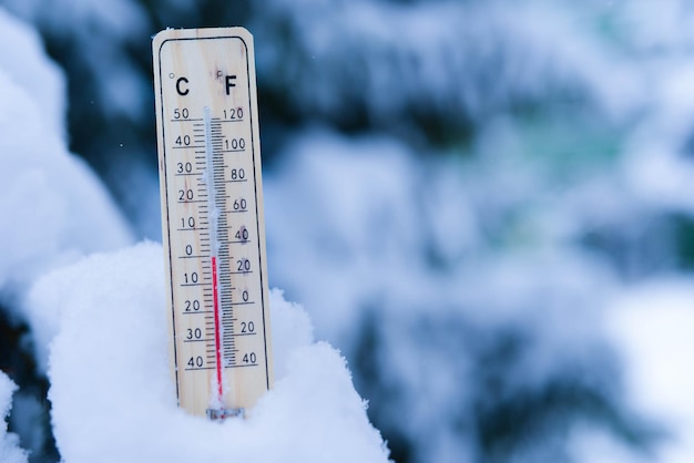 Thermometer on snow with low temperatures in celsius or fahrenheit in winter.